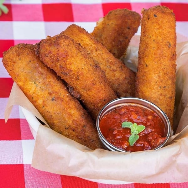 Golden-brown fried mozzarella sticks and a small bowl of marinara sauce with a fresh herb sprig.