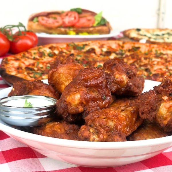 Enzo's Pizzeria's crispy chicken wings with dipping sauce, pizza, and a sub sandwich.