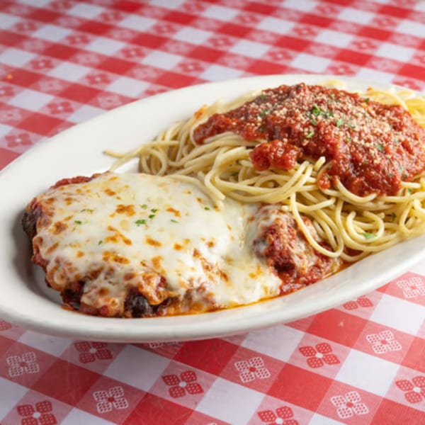 Chicken parmesan with melted mozzarella and spaghetti with marinara sauce on a red and white checkered tablecloth.