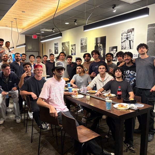 A large group of young men enjoying pizza and drinks at Enzo's Pizzeria.