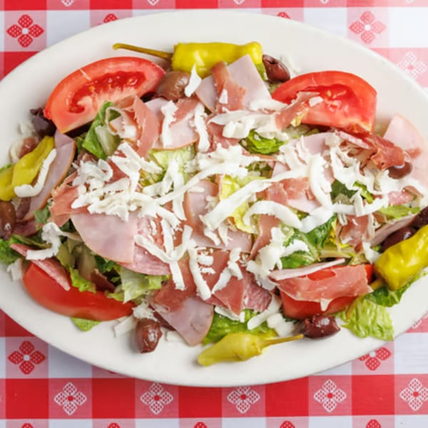 Enzo's Pizzeria antipasto salad with lettuce, tomatoes, olives, ham, salami, and shredded cheese.