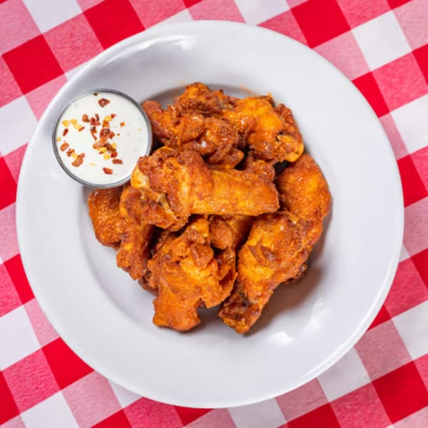 Plate of Enzo's Pizzeria buffalo wings with ranch dressing, on a red and white checkered tablecloth.