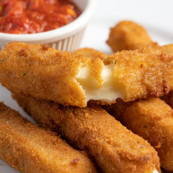 Golden-brown mozzarella sticks with one broken open to show melted cheese, served with marinara sauce.
