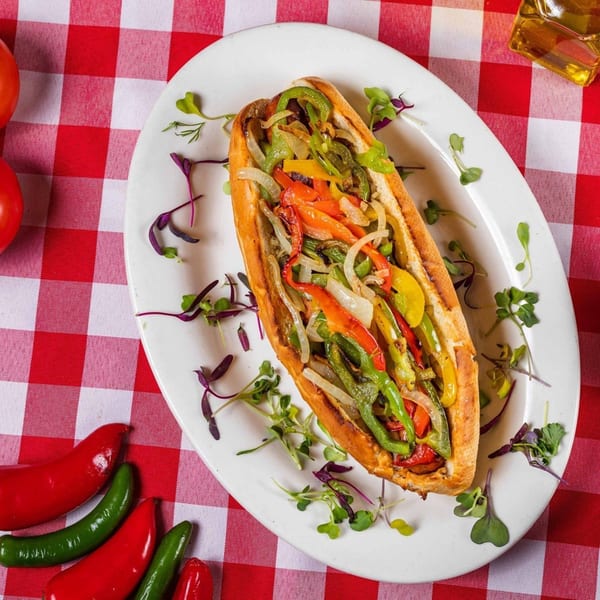 Enzo's Pizzeria's colorful pepper and onion sub on a white plate with a red and white checkered tablecloth.