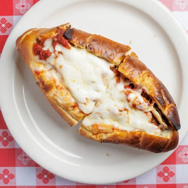 Enzo's Pizzeria's baked calzone, sliced open to reveal melted mozzarella and rich tomato sauce.