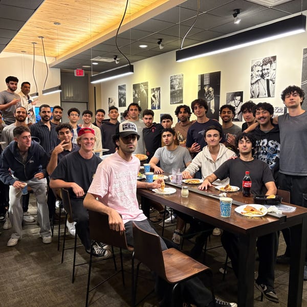 A large group of young men enjoying pizza and drinks at Enzo's Pizzeria.